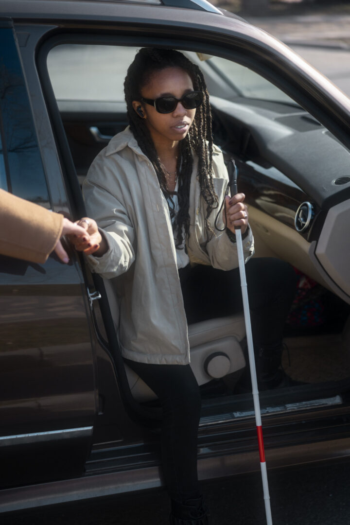 Woman with white cane exiting a car