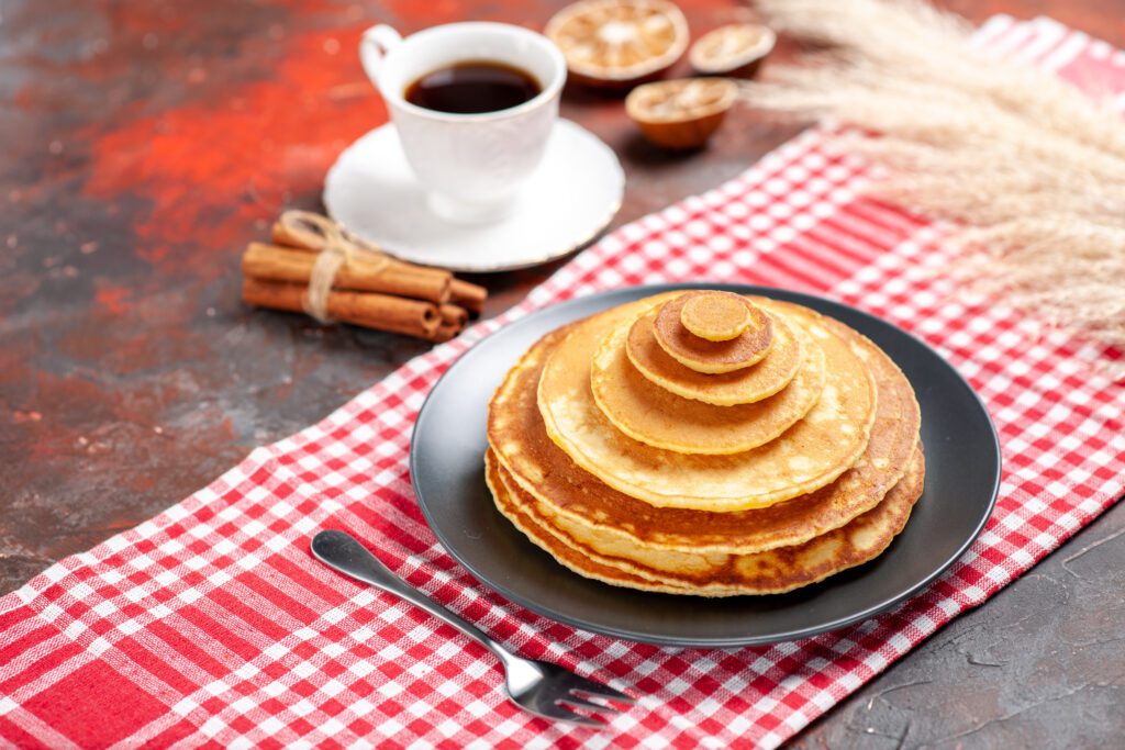 Stack of pancakes and coffee on red check tablecloth